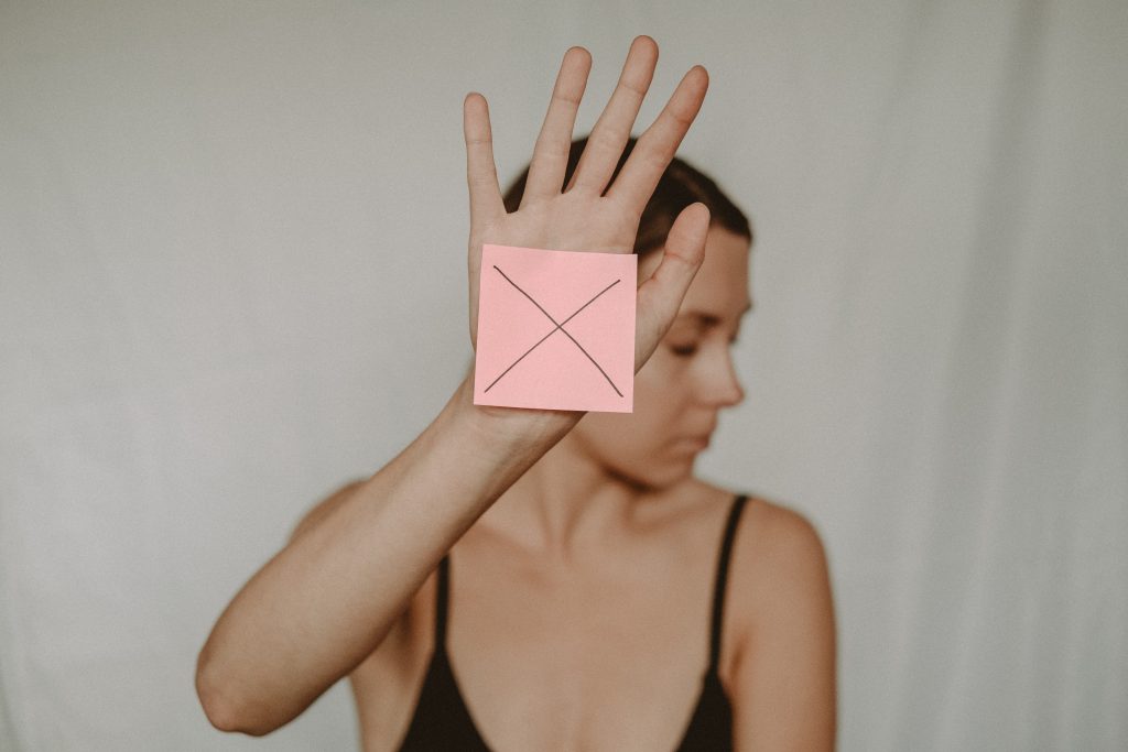 a woman holding a post it note with a cross drawn on it
