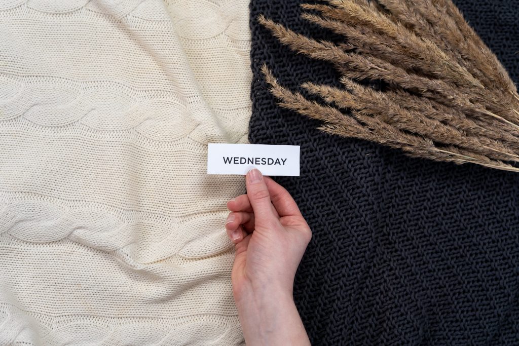 a person holding a label with Wednesday written on it over white and black material